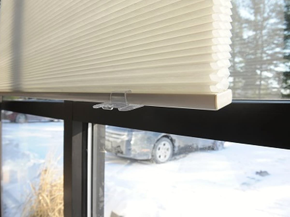 Close-up of the approved cream cellular shade installed on a black-framed window